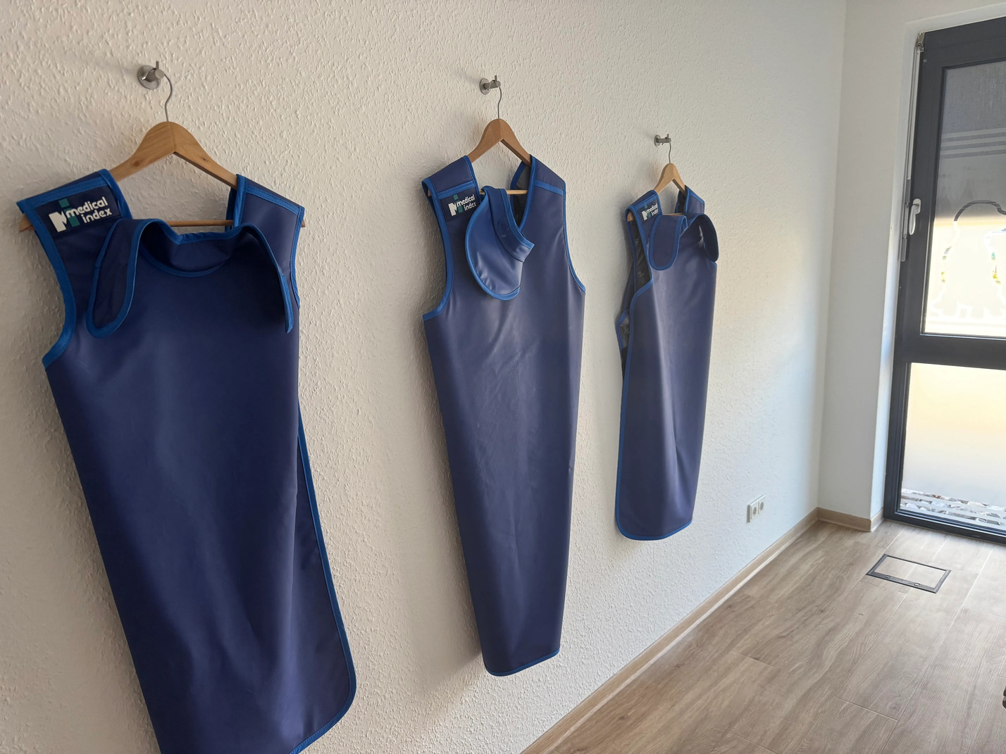 Drei blaue Roentgenschuerzen der Marke Medical Index haengen an einer Wand